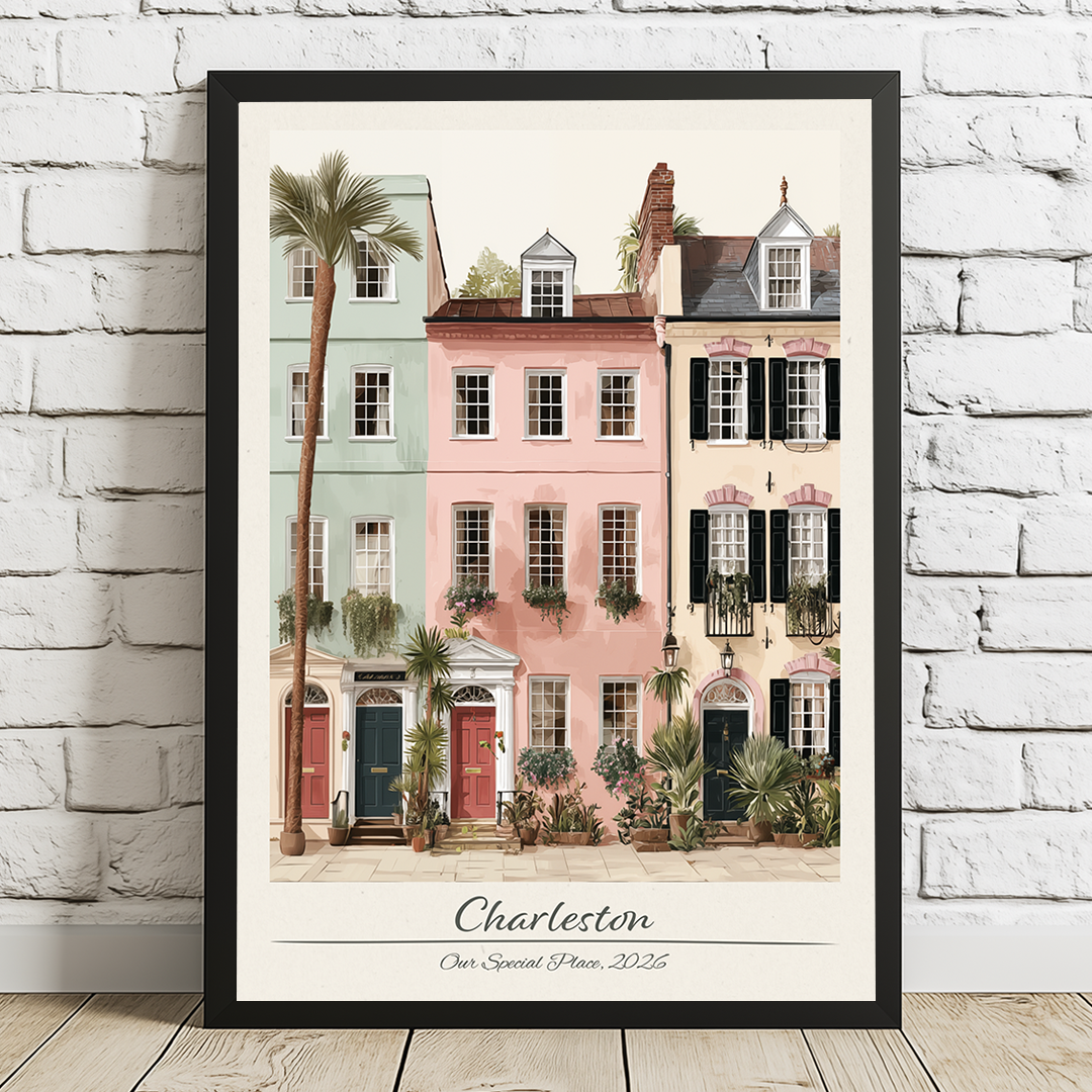 Framed artwork of colorful houses and palm trees in Charleston, displayed on a white brick wall.