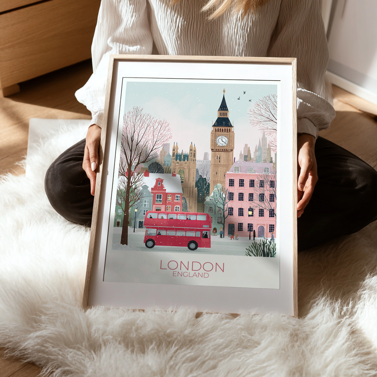 Person holding a framed print of London with Big Ben and a red double-decker bus.