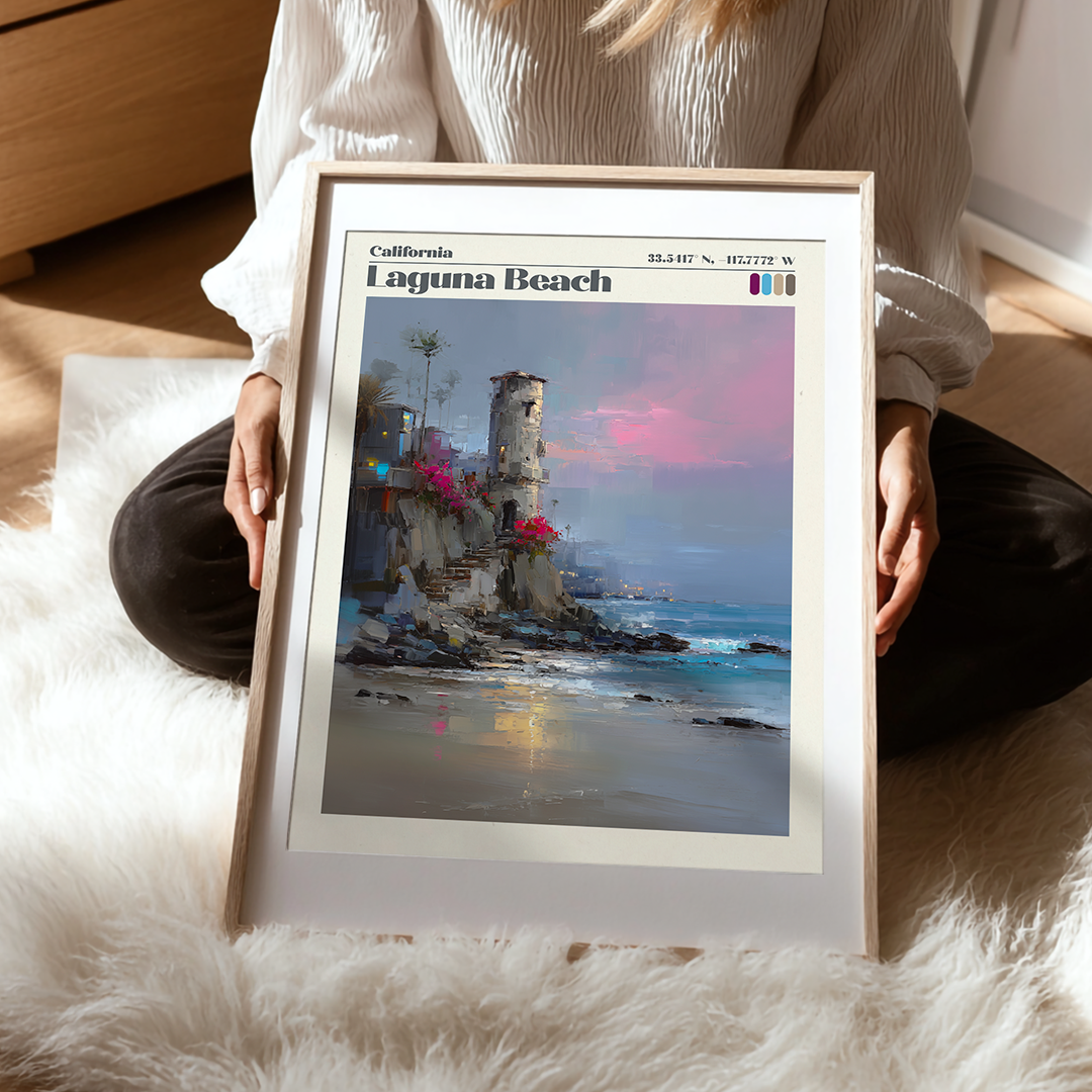 Person holding a framed artwork of Laguna Beach with a scenic coastal scene.