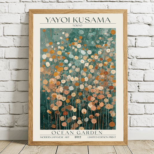 A framed art print of Yayoi Kusama's 'Ocean Garden' poster, leaning against a white brick wall on a light wooden floor. The print features a cream background with a central teal and orange floral pattern, enclosed in a light wood frame.