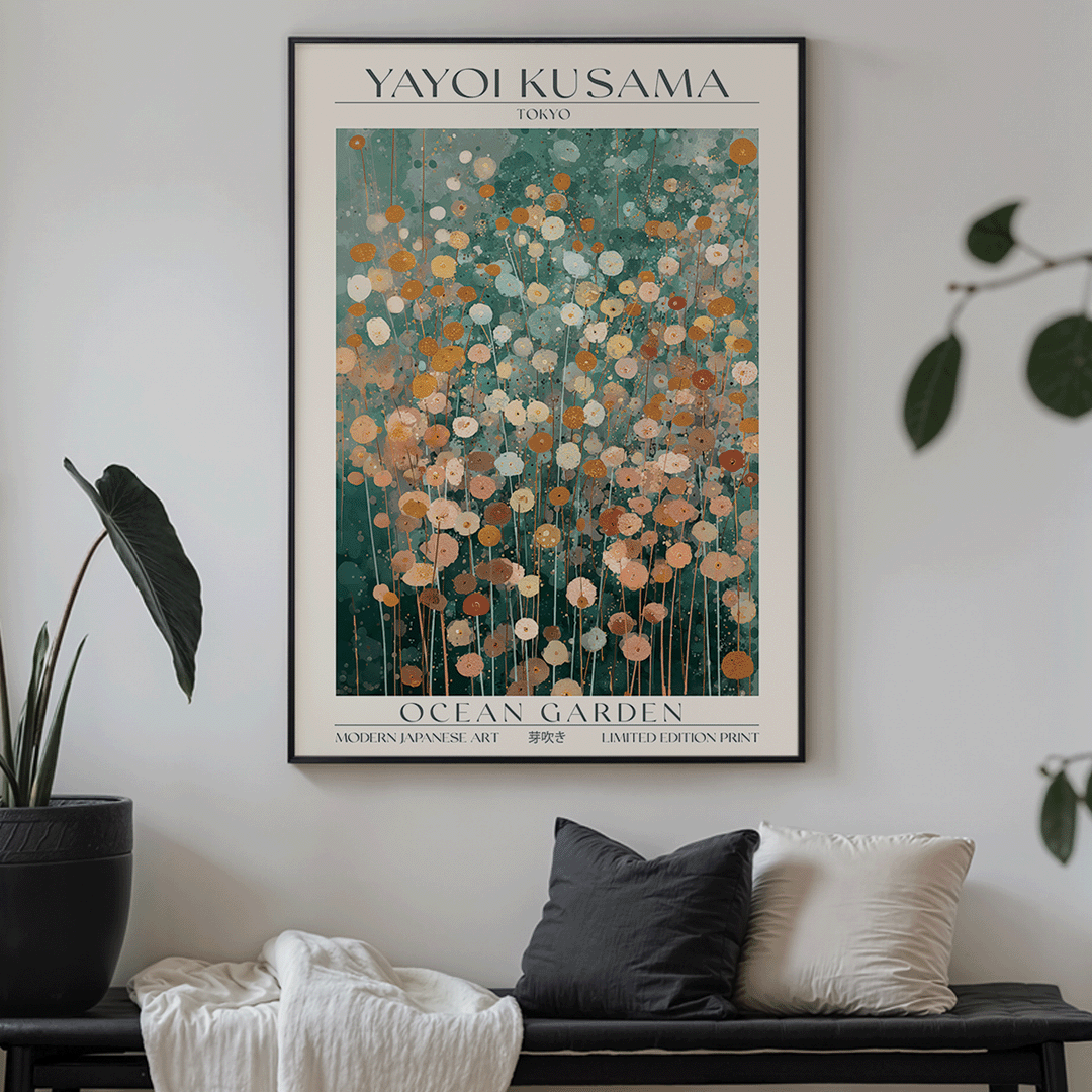 A framed art print titled 'YAYOI KUSAMA OCEAN GARDEN' hangs on a light gray wall above a dark bench with pillows and a throw blanket. The print features an abstract floral pattern in teal, orange, cream, and gold tones, with the artist's name and edition text visible.