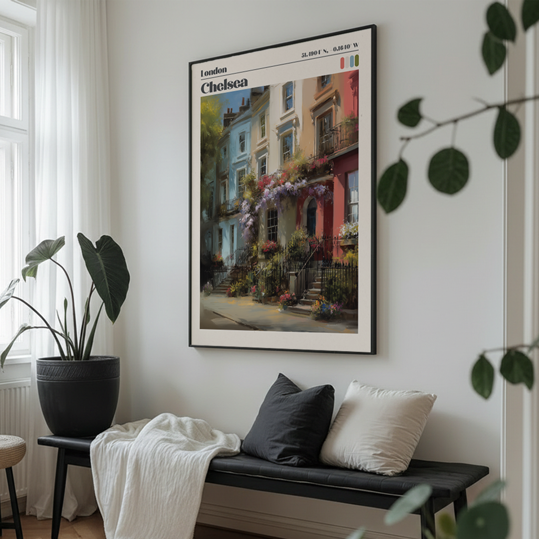 Framed artwork of a street scene in Chelsea, London, above a bench with cushions in a room with plants.