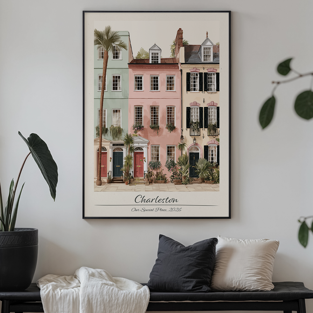 Framed artwork of Charleston buildings on a wall above a sofa with decorative pillows.