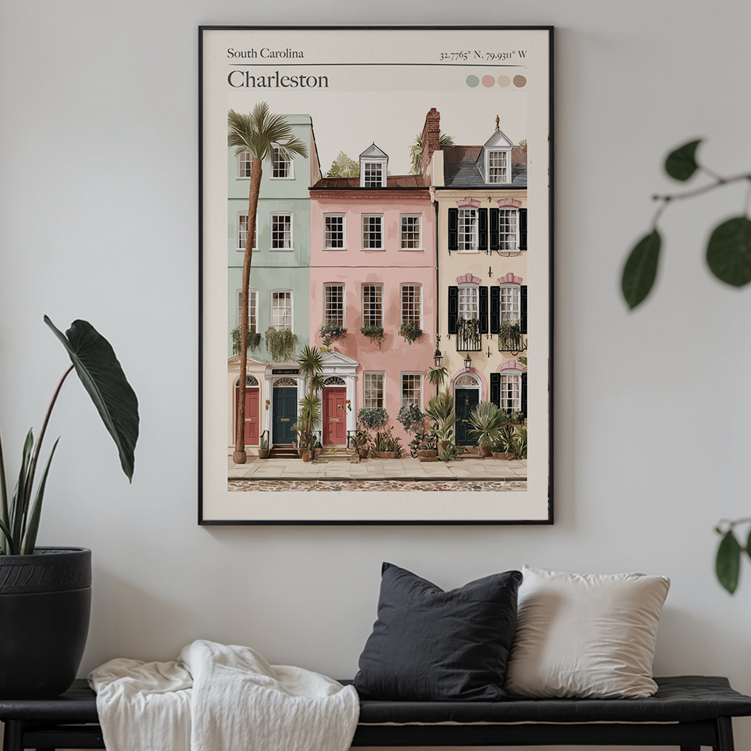 Framed artwork of Charleston buildings on a wall above a sofa with decorative pillows.