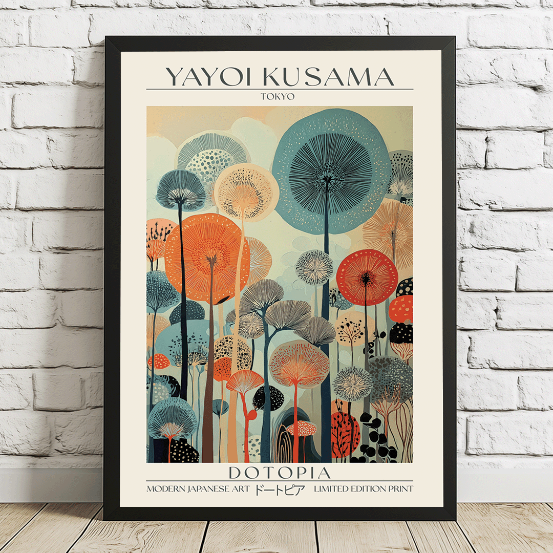 A framed art print of Yayoi Kusama's 'Dotopia' poster, leaning against a white brick wall on a light wooden floor. The poster features a black frame, cream background, and a colorful illustration of stylized dandelions in shades of teal, orange, red, and gray.