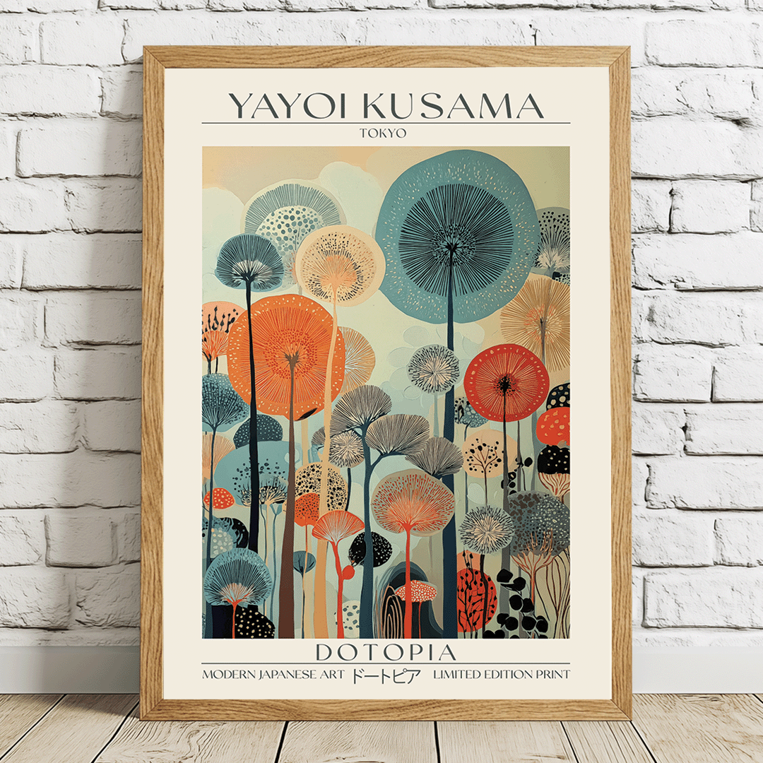 A framed art print of Yayoi Kusama's 'Dotopia' poster, leaning against a white brick wall on a light wooden floor. The print features a colorful retro illustration of stylized dandelions in shades of teal, orange, red, and beige, enclosed in a light oak wood frame.