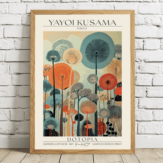 A framed art print of Yayoi Kusama's 'Dotopia' poster, leaning against a white brick wall on a light wooden floor. The print features a colorful retro illustration of stylized dandelions in shades of teal, orange, red, and beige, enclosed in a light oak wood frame.