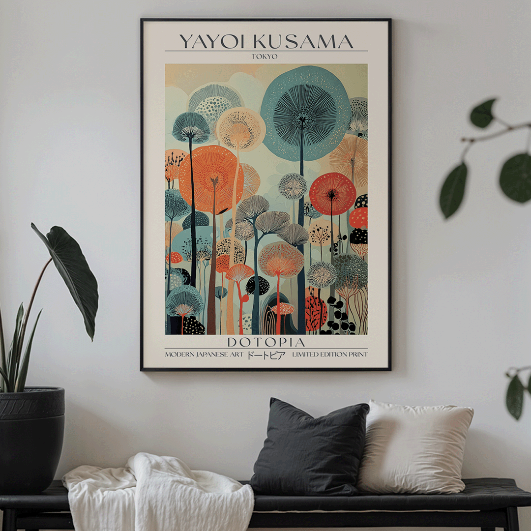 A framed art print featuring a stylized botanical illustration with the text 'YAYOI KUSAMA' at the top and 'DO TOPIA' at the bottom, displayed on a light gray wall above a bench with pillows and plants.