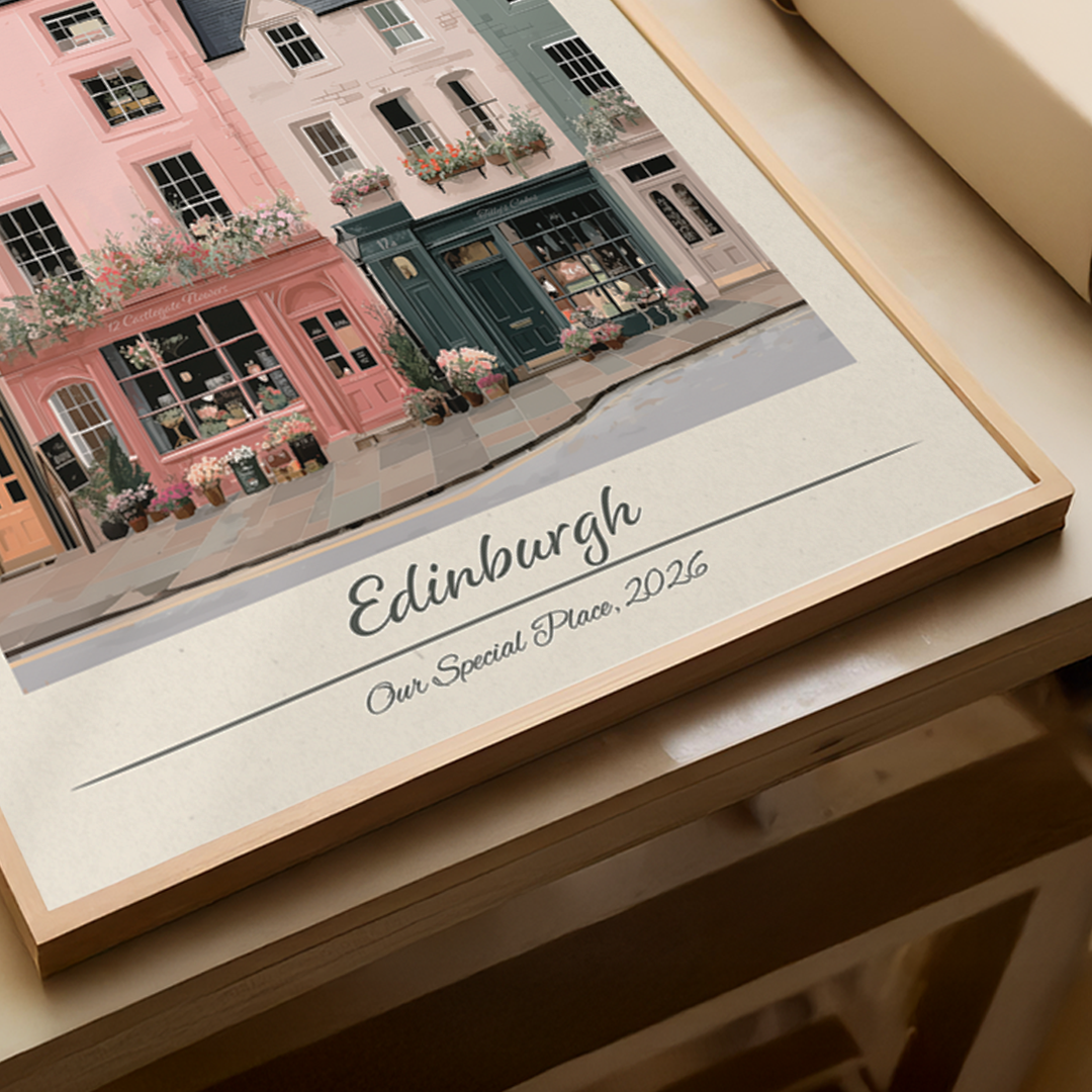 Framed artwork of a street scene with buildings labeled 'Edinburgh' on a wooden surface.