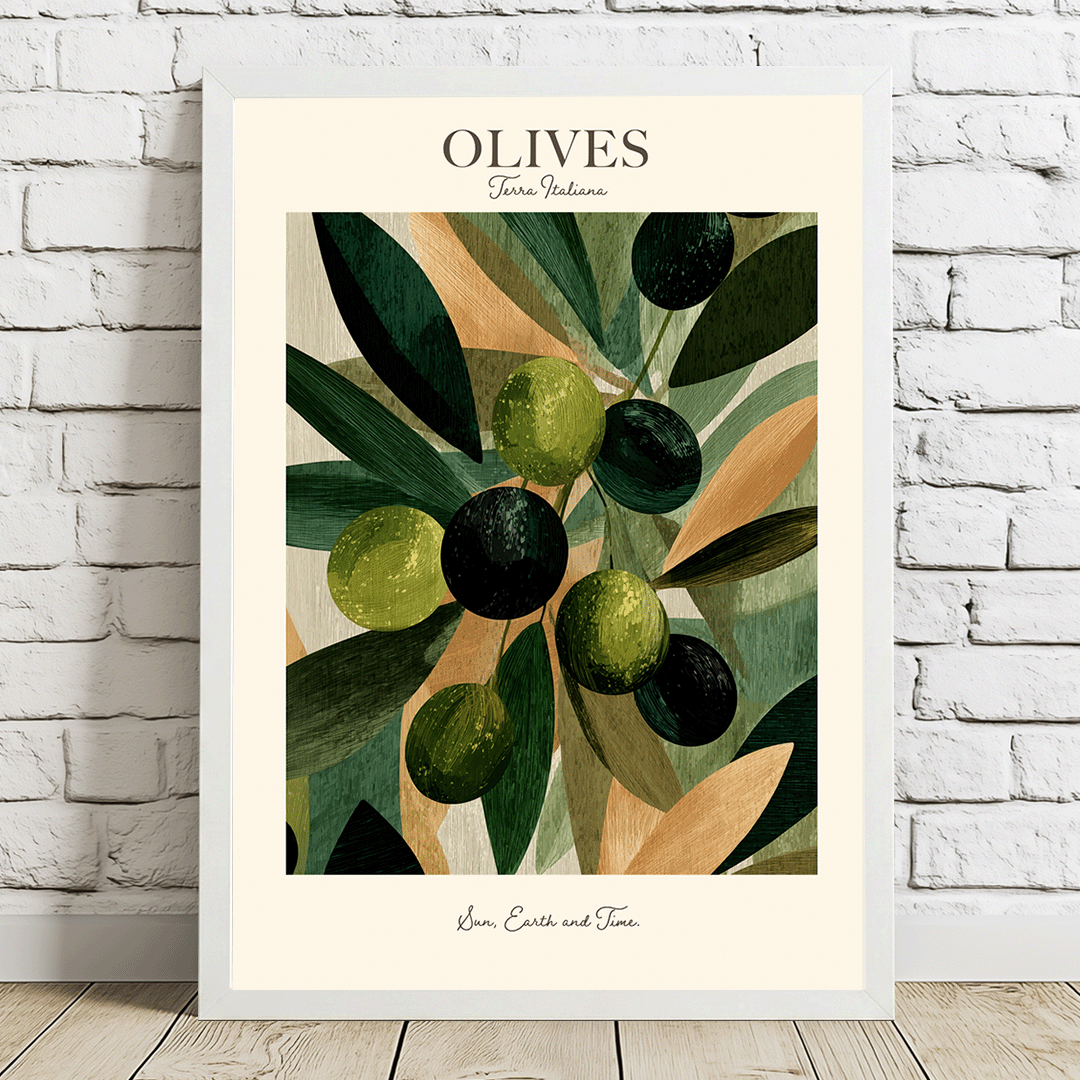 A framed art print featuring a stylized illustration of olives on an olive branch, leaning against a white brick wall on a light wood floor. The print has a cream border with the word 'OLIVES' and the signature 'Jana Costa and Toni' at the bottom.