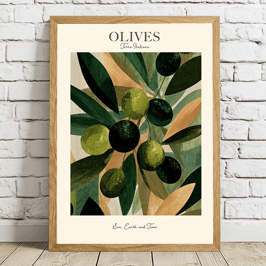 A framed art print featuring an illustration of green and black olives on leaves, titled 'OLIVES' with 'Gourmand Nature' written below, leaning against a white brick wall on a light wood floor.