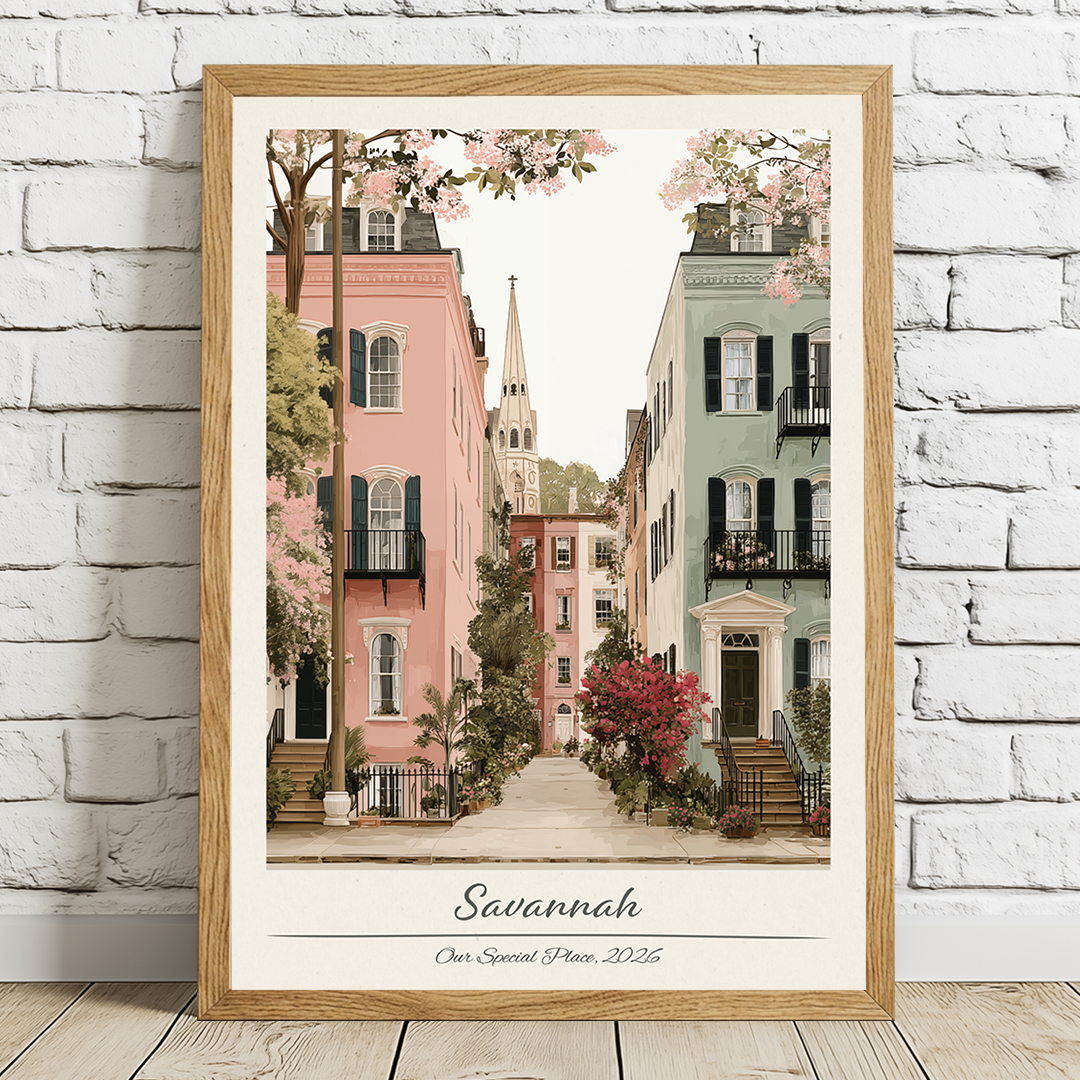 Framed artwork of a street scene in Savannah with cherry blossoms, displayed on a white brick wall.